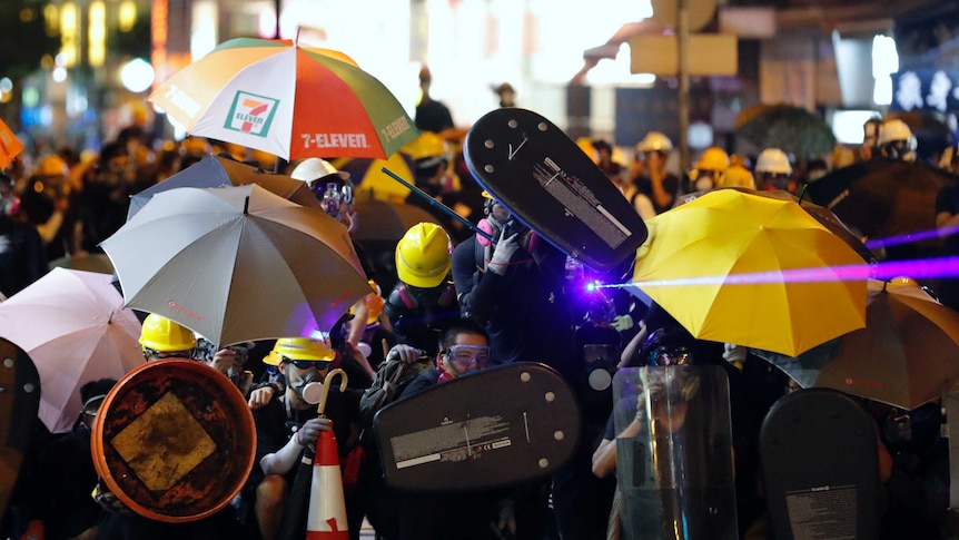 Protesters shine a laser beam as they form up in gas masks and umbrellas during a confrontation with police in Hong Kong