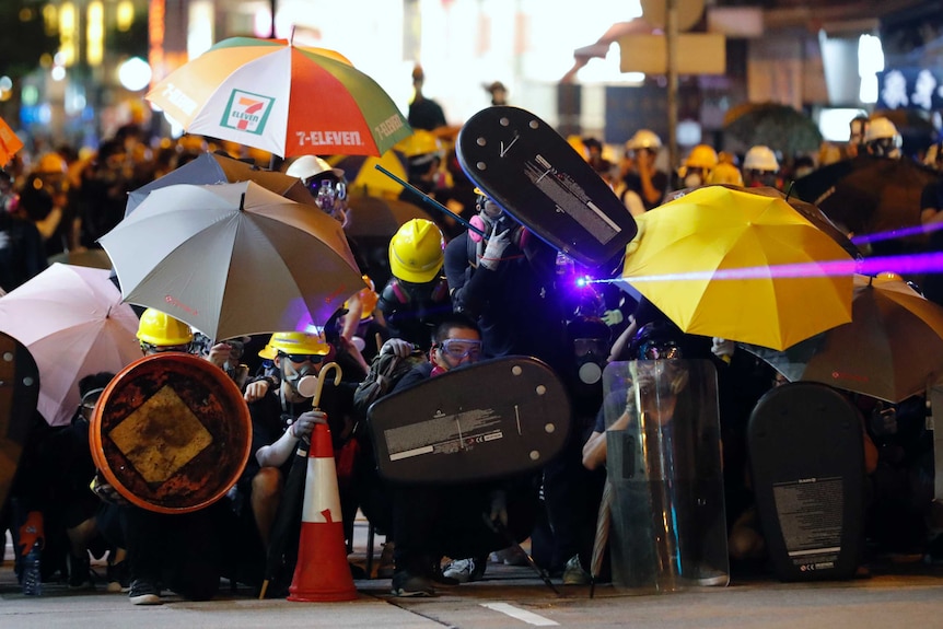 Protesters shine a laser beam as they form up in gas masks and umbrellas during a confrontation with police in Hong Kong.