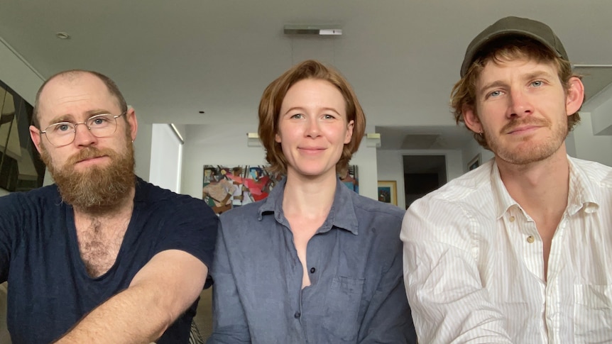 Three young people smile at the camera.