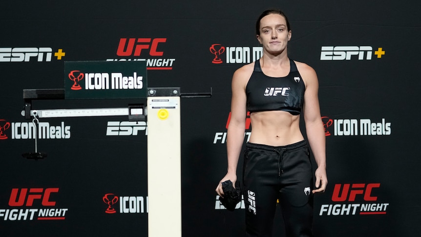 UFC fighter Aspen Ladd stands next to the scales at a weigh-in.