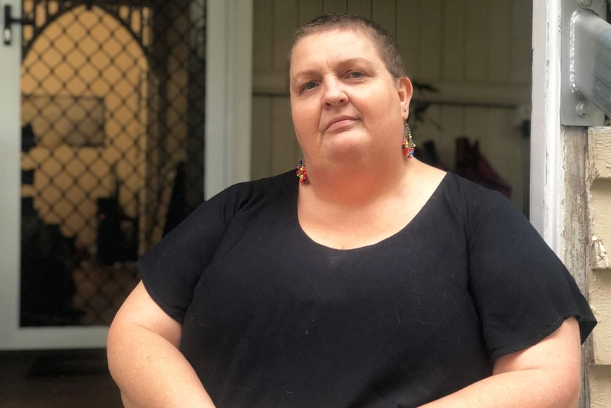 Sandy Walker stands outside a house.