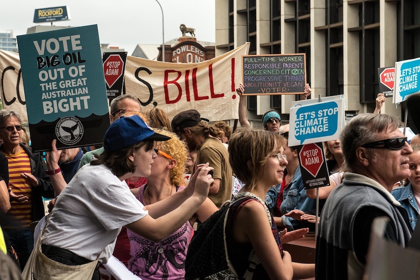 Protesters wave signs and placards urging action on several environmental issues.