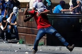 A Palestinian uses a sling to hurl a stone towards Israeli police during clashes in Shuafat, Jerusalem.