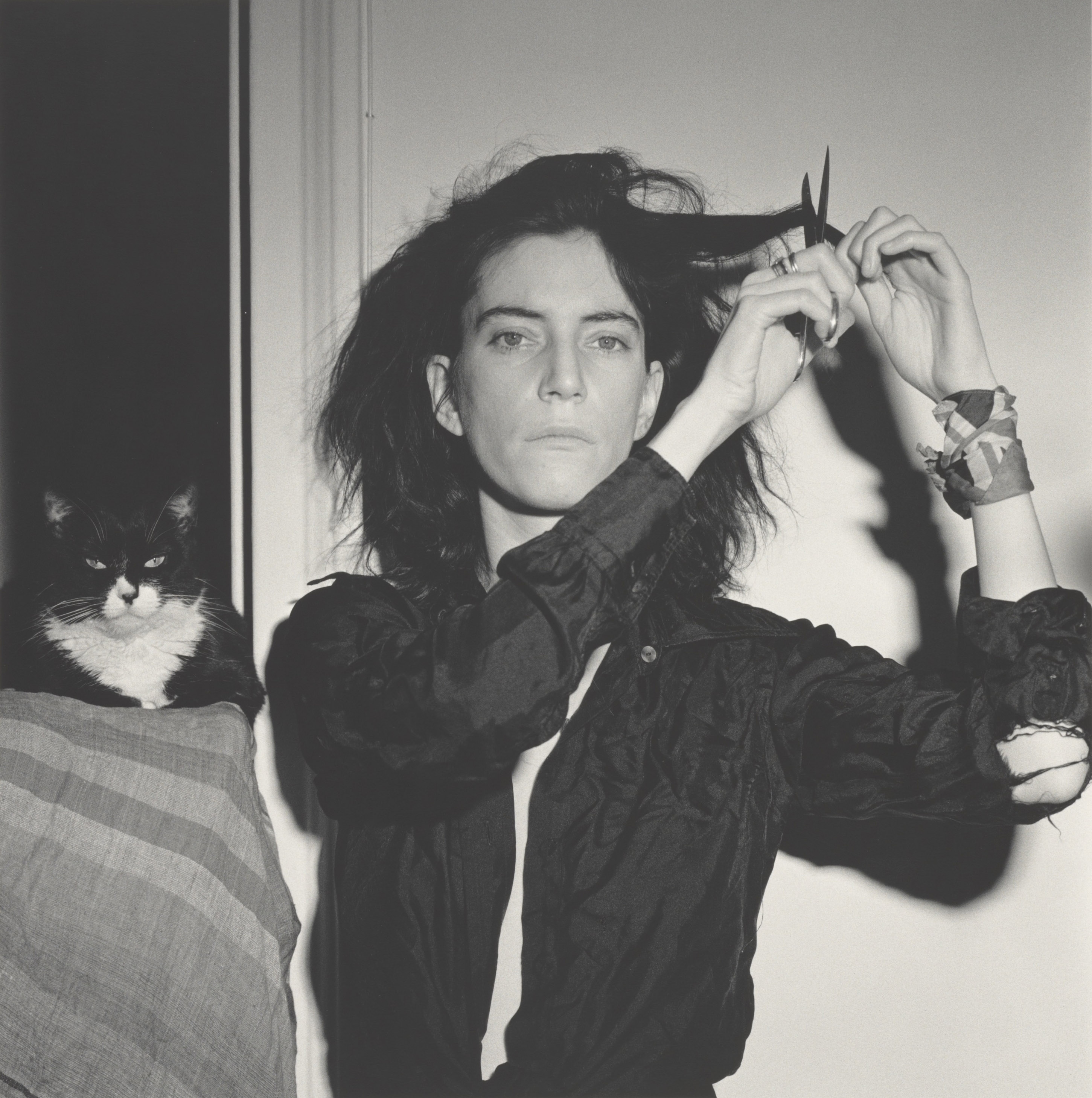 Black and white photograph of a cat and Patti Smith cutting her hair.