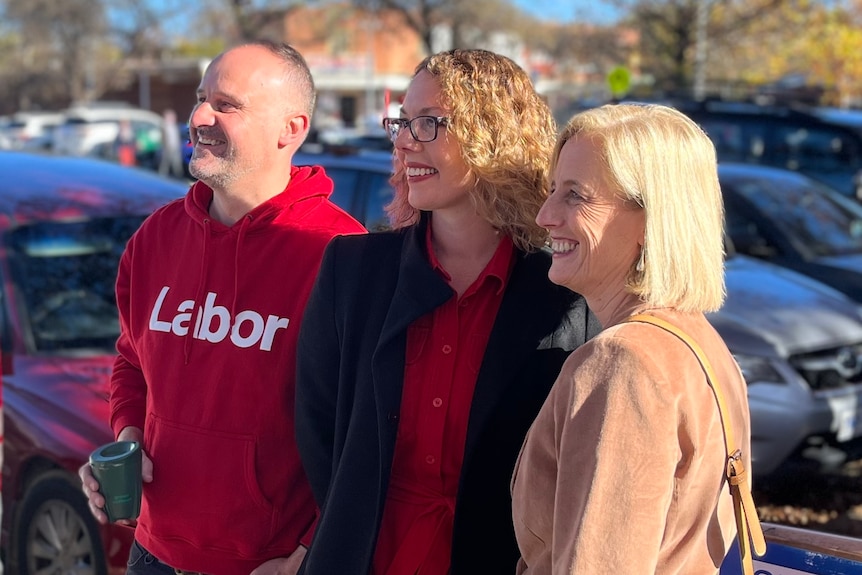 A man wearing a shirt with the word 'Labor' and two woman stand together smiling.