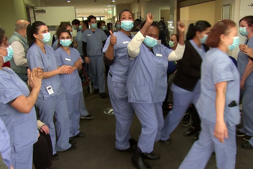 Nursing home staff wearing masks and masks give thumb up and clap after containing a coronavirus outbreak at the facility.