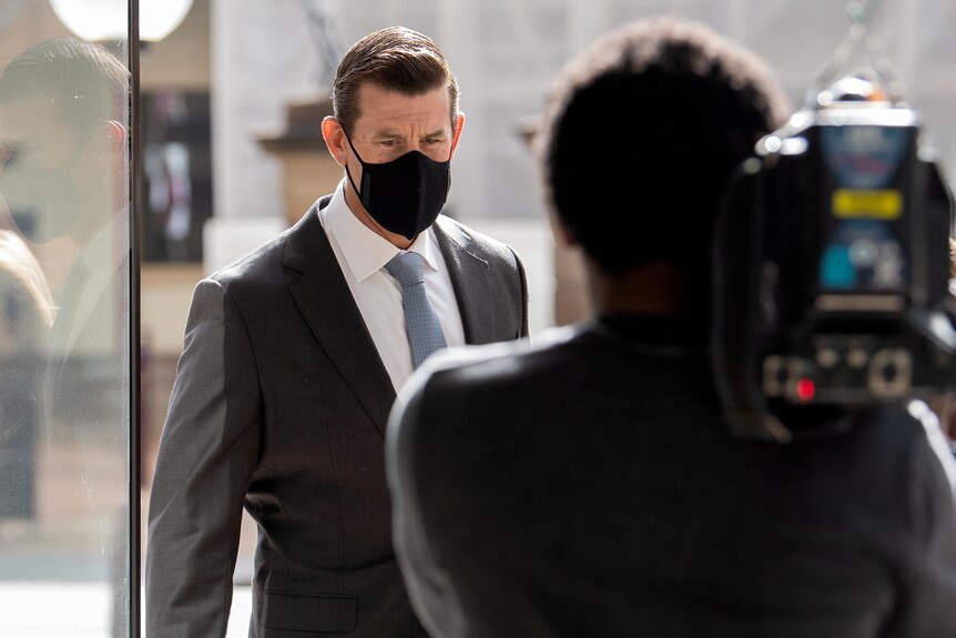 a man wearing a mask walking through doors with a camera pointed at his face