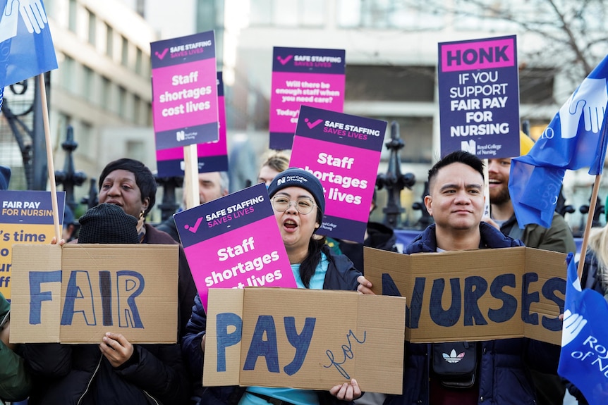 Nurses holding placards outside a hospital 