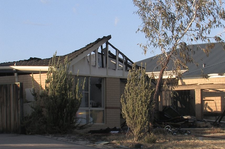 A house stands with its roof collapsed in after a fire.