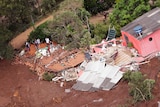 An aerial view shows a destroyed house surrounded by mud after a dam collapse.
