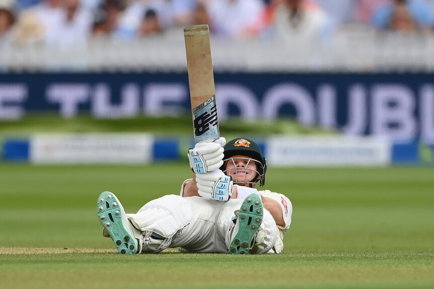 Australia batter Steve Smith points his bat in the air while lying on the ground during an Ashes Test at Lord's.