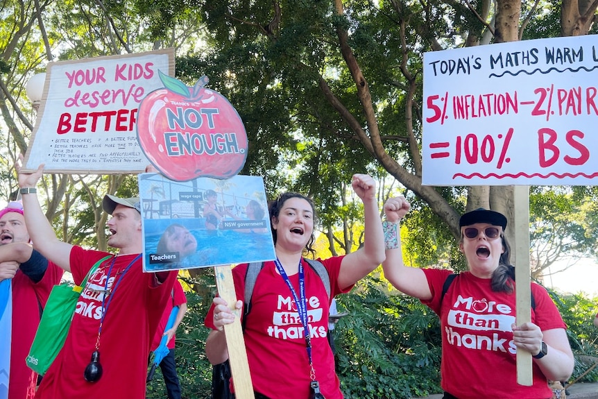 People wearing matching shirts hold signs and yell