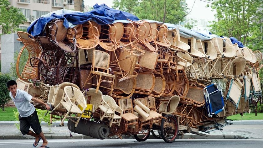 A man pulls a cart loaded with chairs in Shanghai