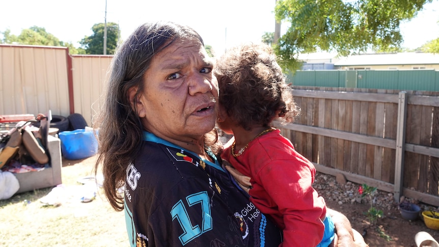 An Indigenous elder holds a young child
