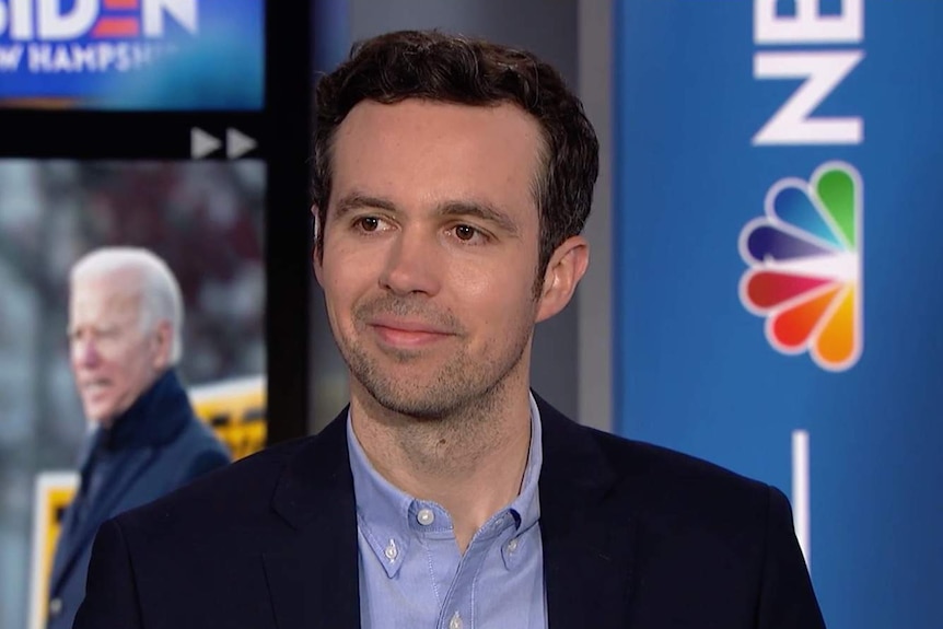 John Hendrickson smiles as he sits on an NBC News set.