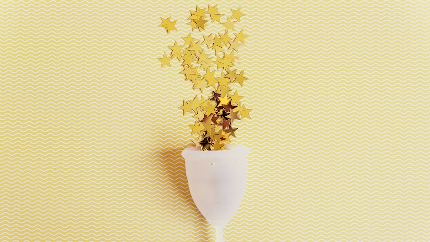 Menstrual cup with sparkling stars on yellow background.