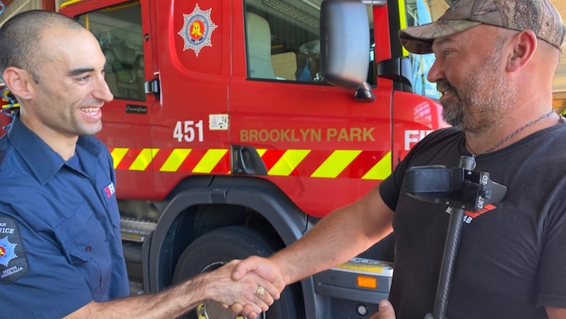 Adelaide firefighter Justin Ocenasek shakes hands with metal detectorist Bruce Phillips.