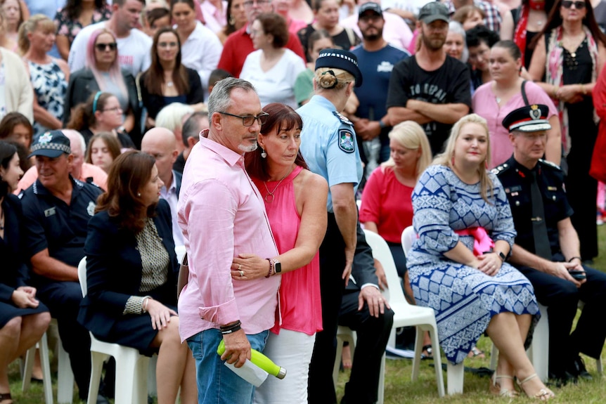 Two people dressed in pink hugging each other in a crowd