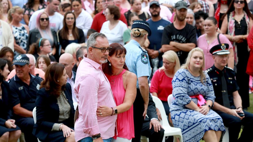 Two people dressed in pink hugging each other in a crowd