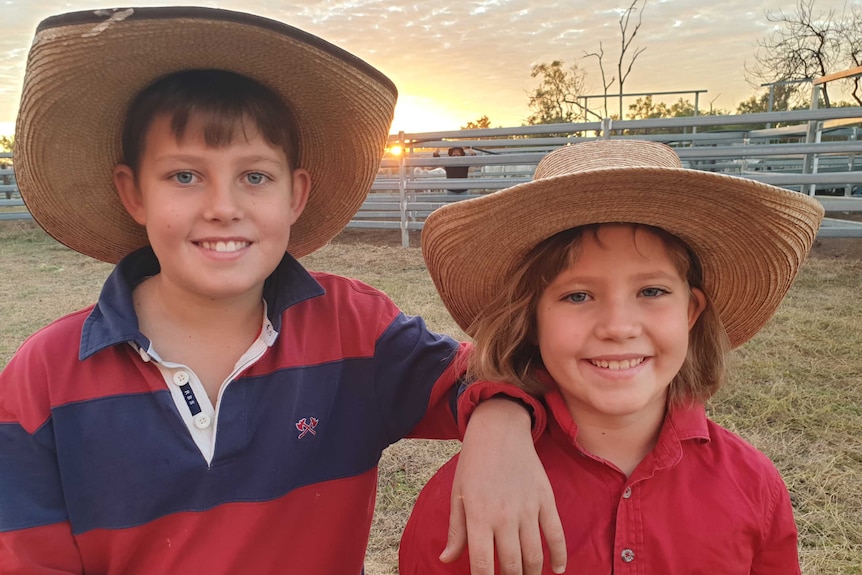 Boy and girl with wide-brimmed hats on a farm