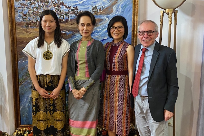 Three women and a man stand next to each other smiling.