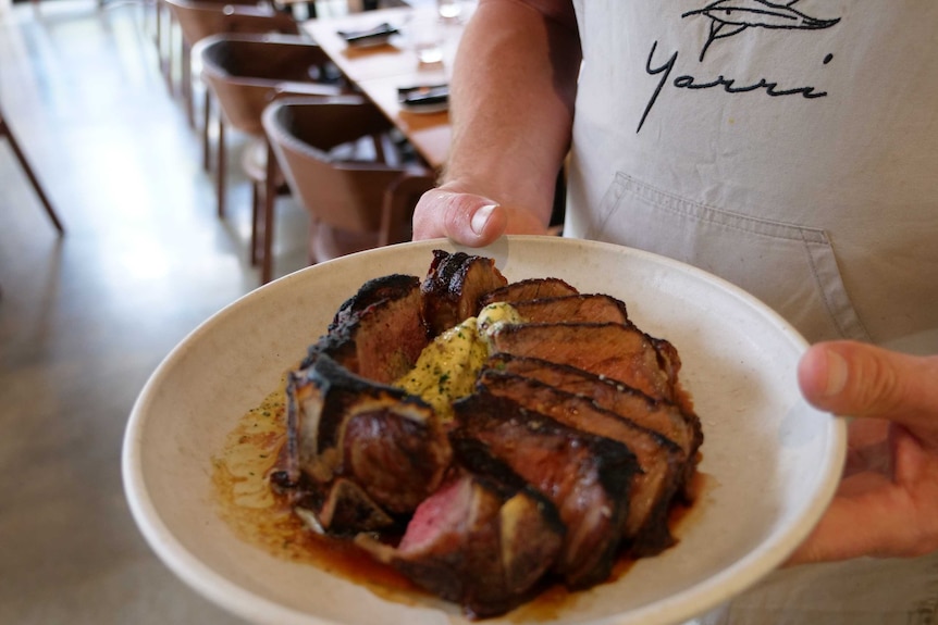 A waiter holds a plate of regenerative beef