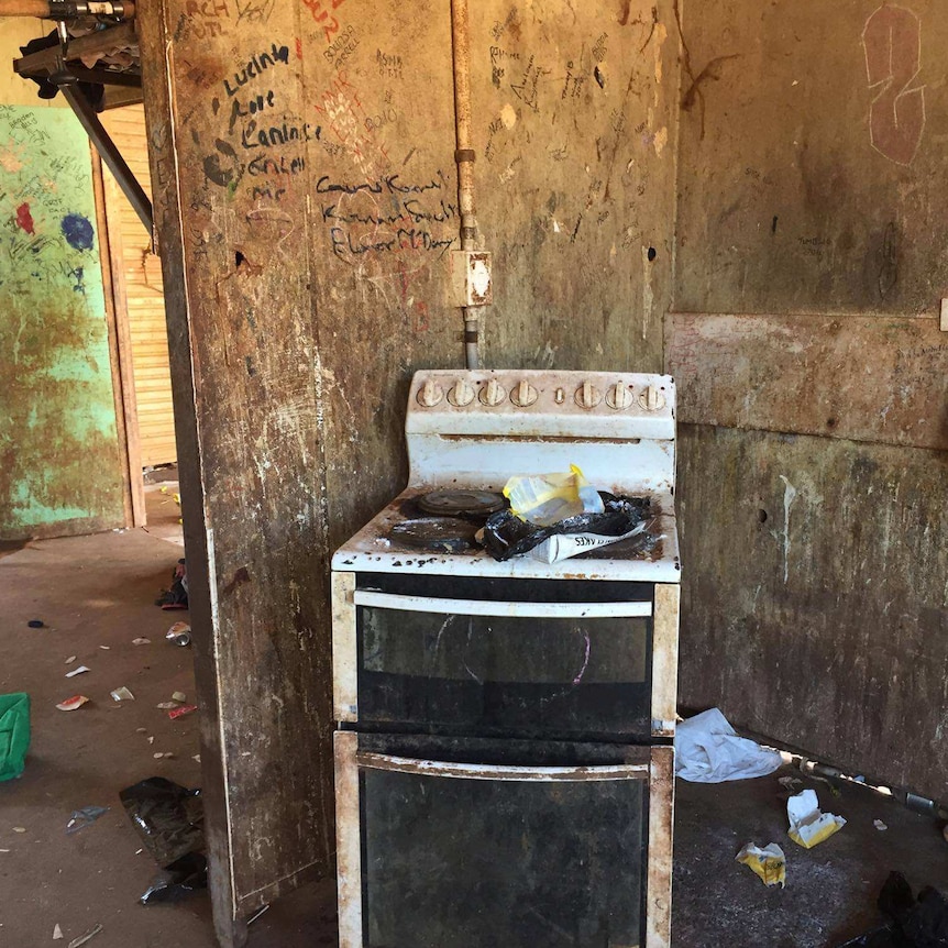 A graffitied kitchen featuring an absolutely filthy oven.
