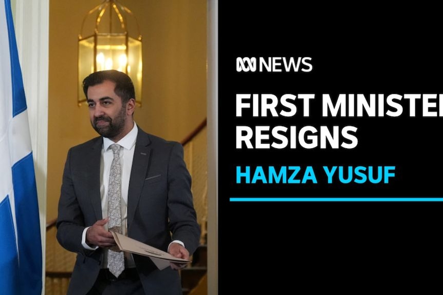 First Minister Resigns, Hamza Yusuf: A man carrying documents walks past a Scottish flag.