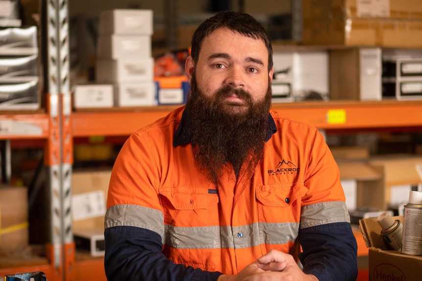 A tradesman in hi vis, Steve Fordham, looks toward the camera in his workshop