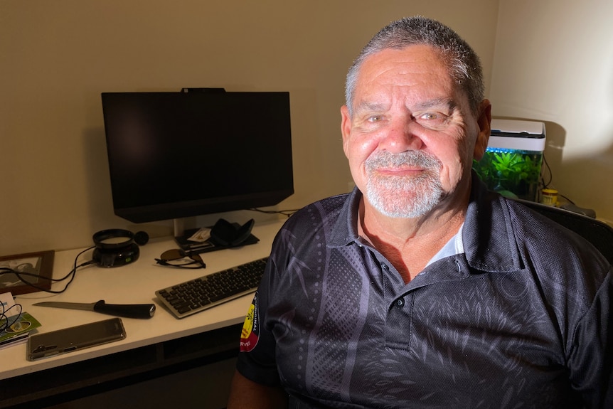 An Aboriginal man smiles at the camera in an office. 