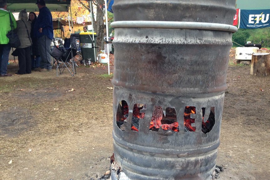 A fire is burning in a drum with CFMEU carved out of it