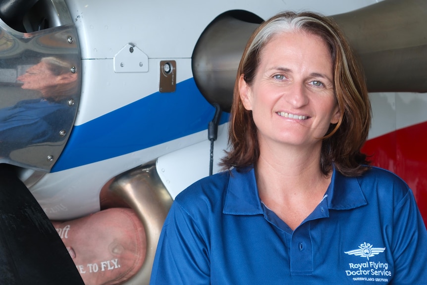 Woman smiles at camera standing in front of plane