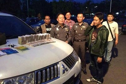 A Thai smuggler is surrounded by police officers.