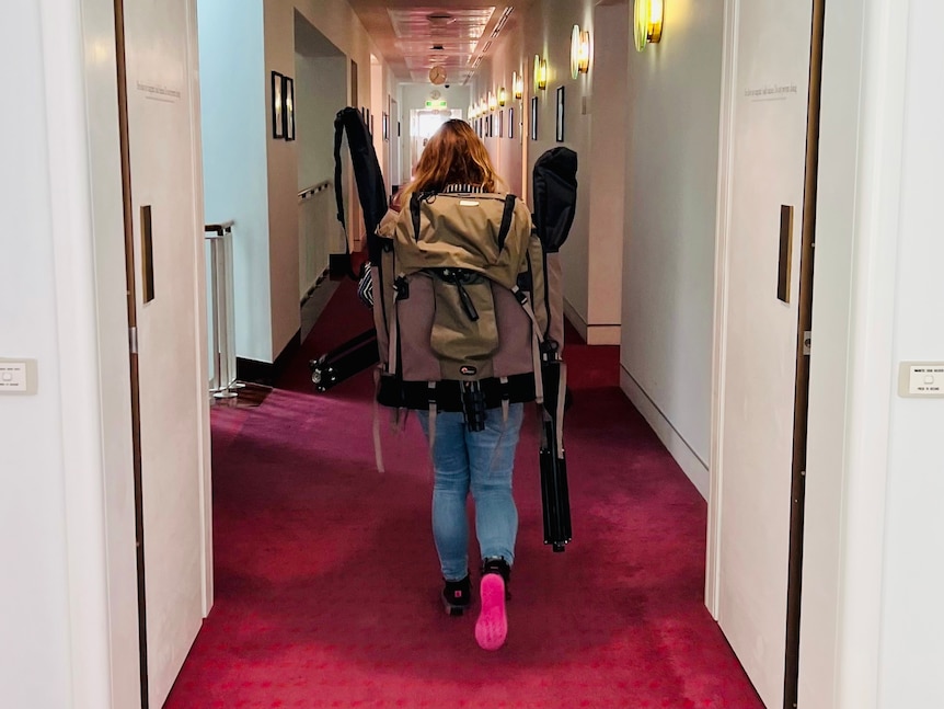 Jessicah walking through the corridors of Parliament with a giant backpack on her back.