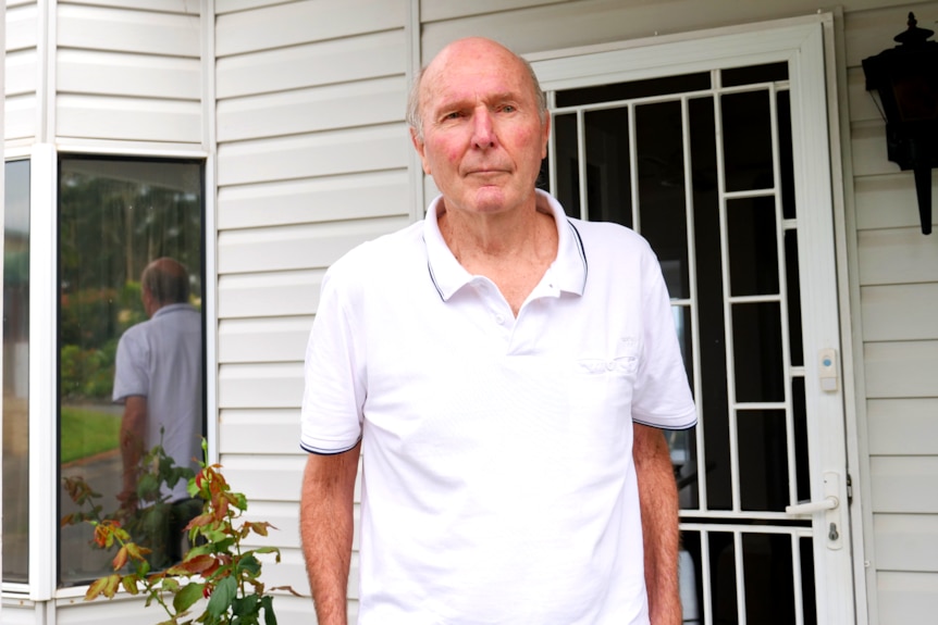 Man slightly looks to the side of the camera outside of his home