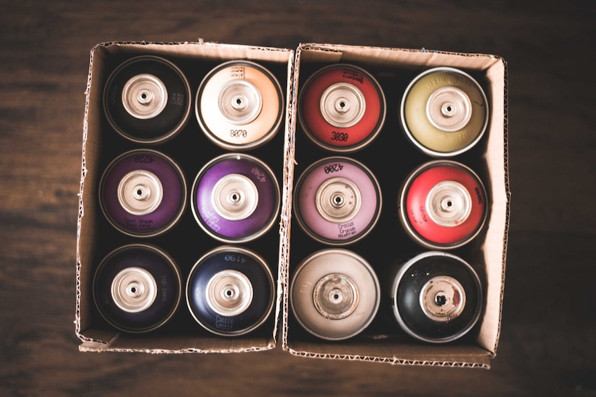 Two boxes of old aerosol spray-paint cans photographed from above.
