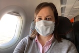 Photo of reporter Rachel Pupazzoni on a plane wearing a protective mask.