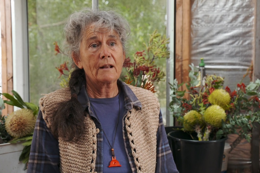 Photo of a woman talking surrounded by flowers.