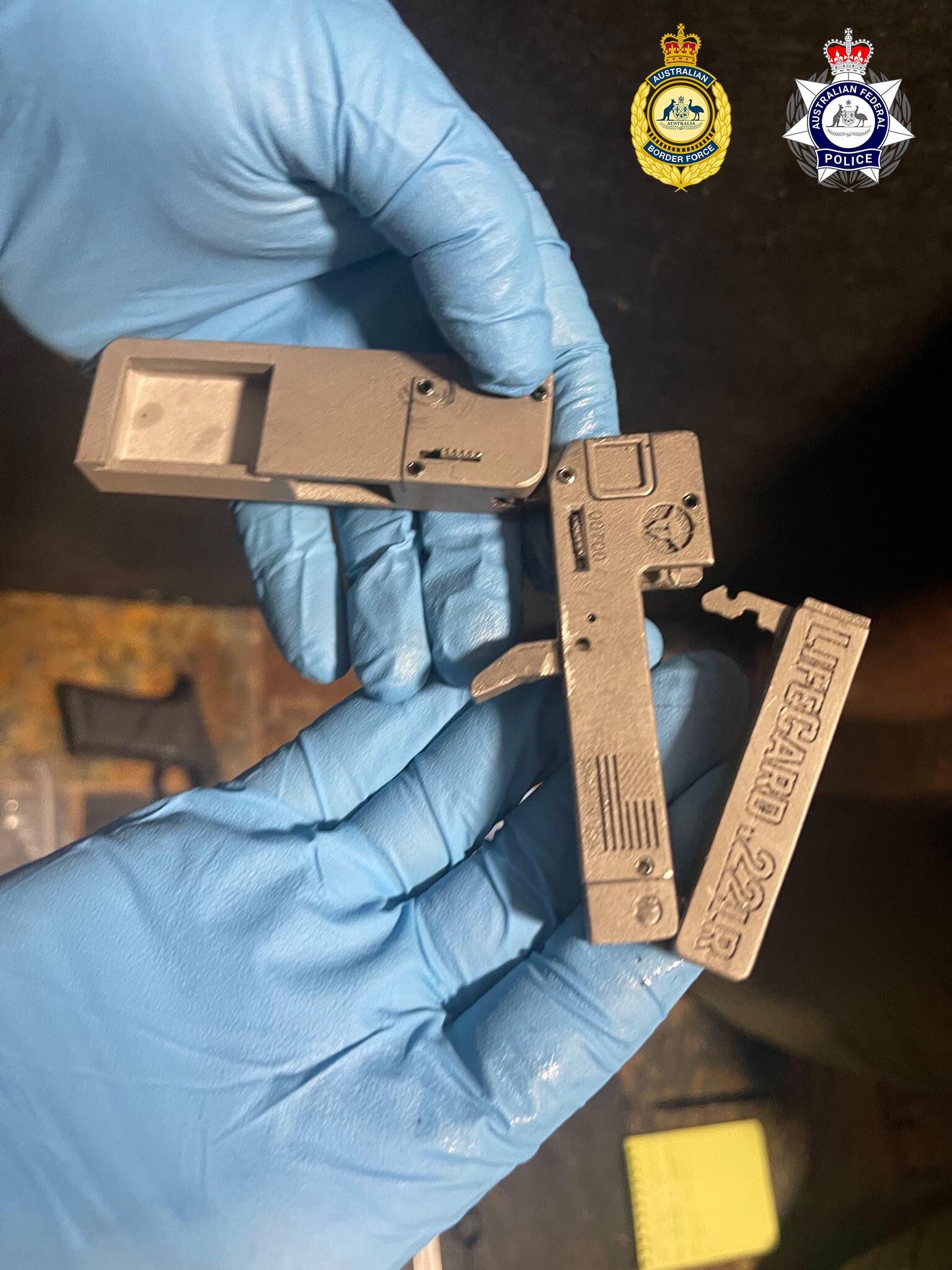 Blue gloved hands holding a gun part. 