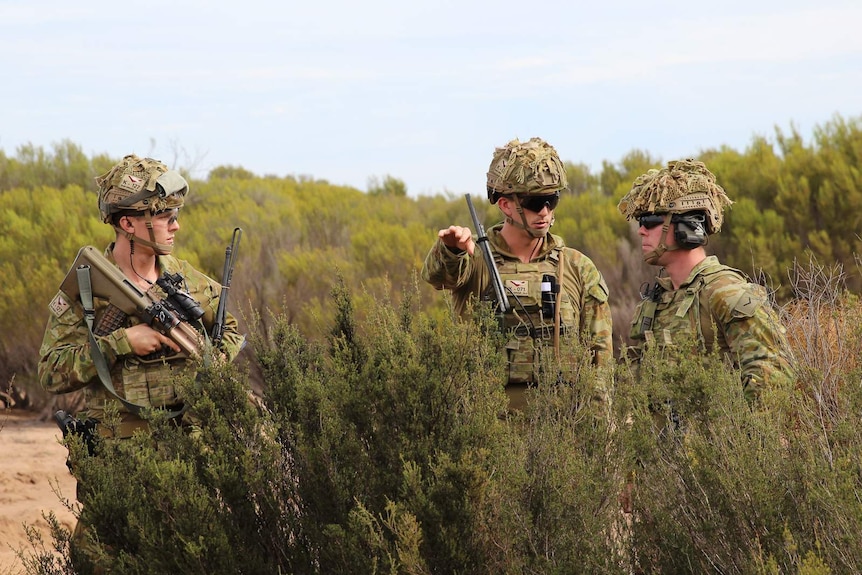 Three soldiers take part in a live fire training scenario.