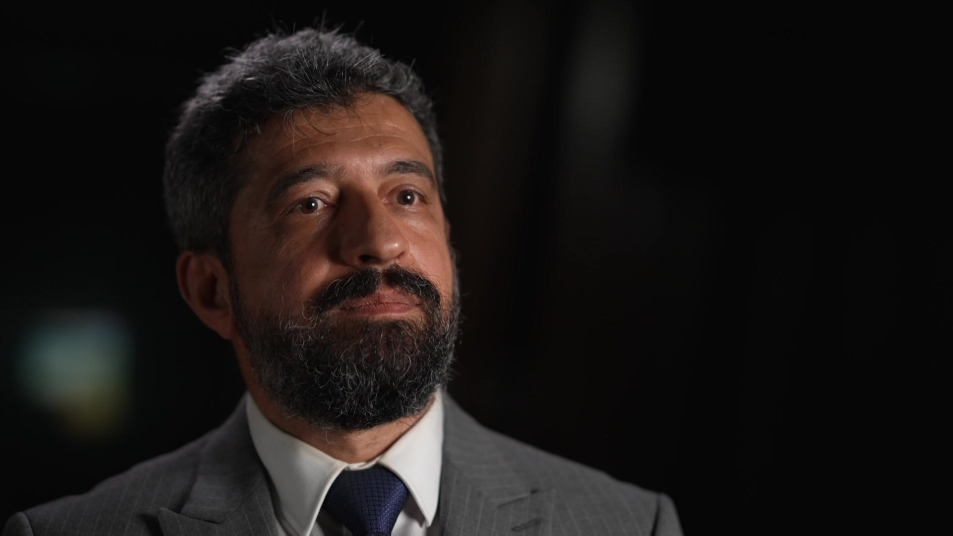 Man wearing a grey suit with a navy tie. 
