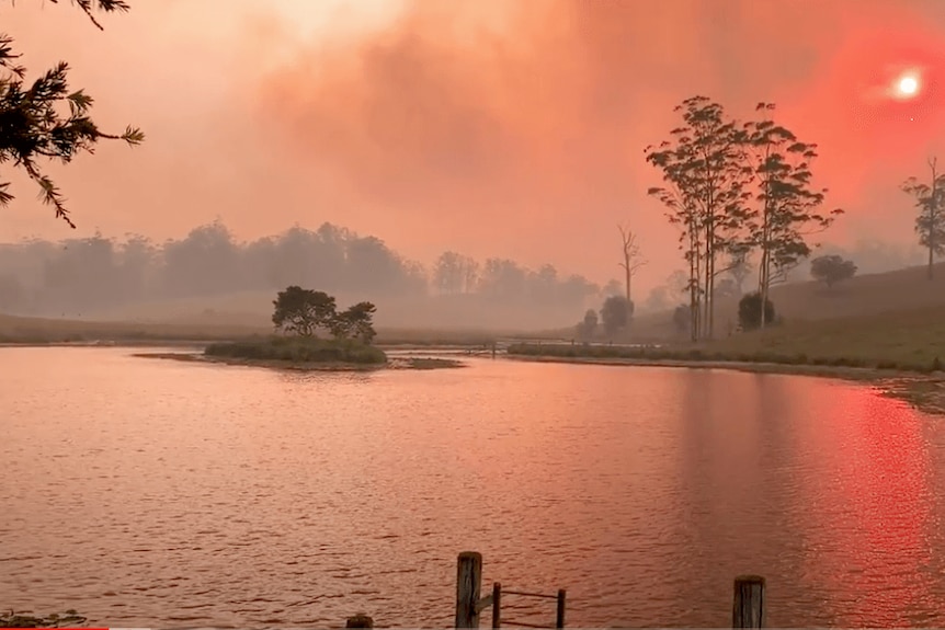 A dam and farm covered by smoke and an eerie red light.