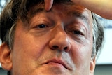 Stephen Fry listens during a press conference.