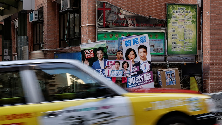 Pedestrians walk past a poster promoting a candidate during Hong Kong election.