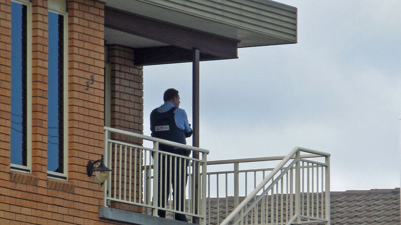 Tasmanian police officer stands on a house landing during a siege at West Moonah.