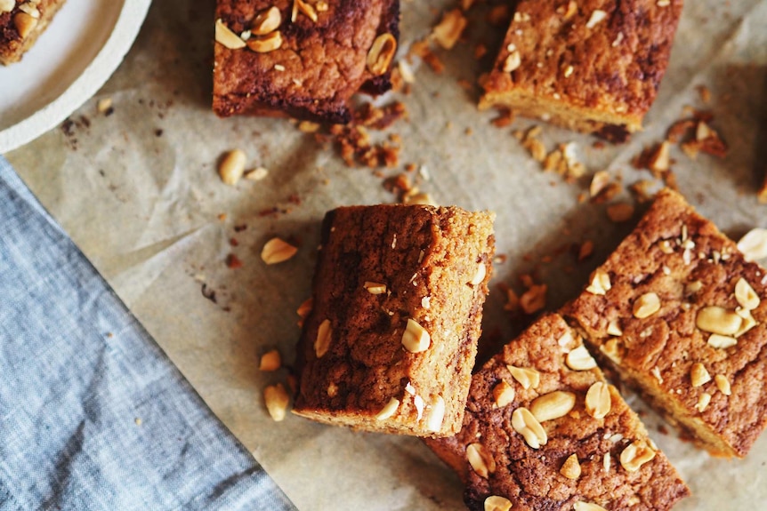 Slices of peanut butter blondies on a baking sheet topped with salted peanuts, an easy sweet treat.