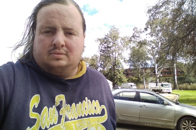 Selfie of a man with a car in the background
