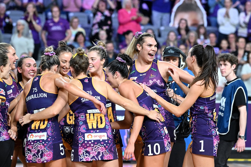Queensland Firebirds players smile and hug each other