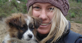 Justine Damond is wearing a beanie and winter jacket as she smiles and poses with a small dog.
