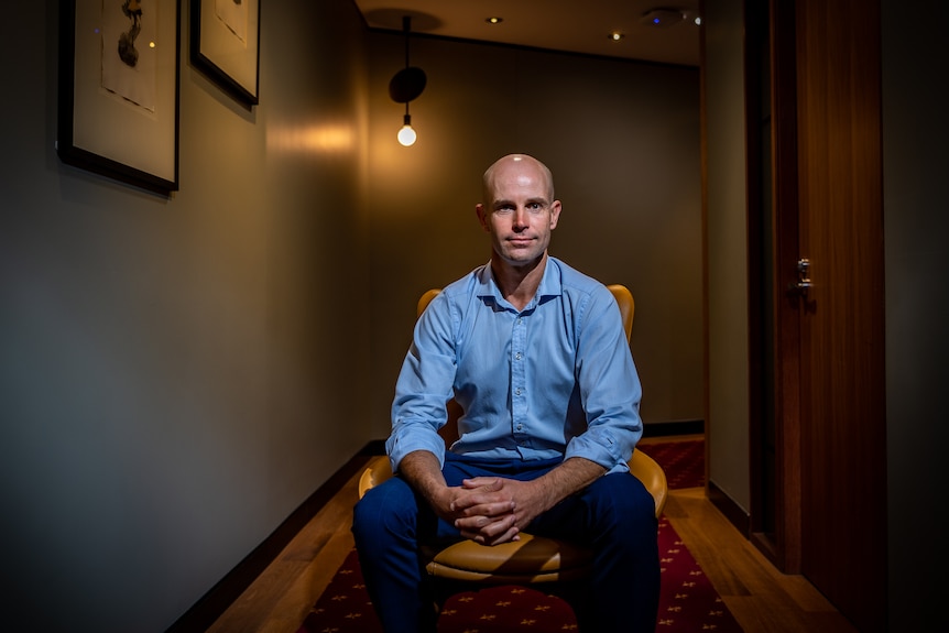 A man in a boardroom setting with a light in the background.